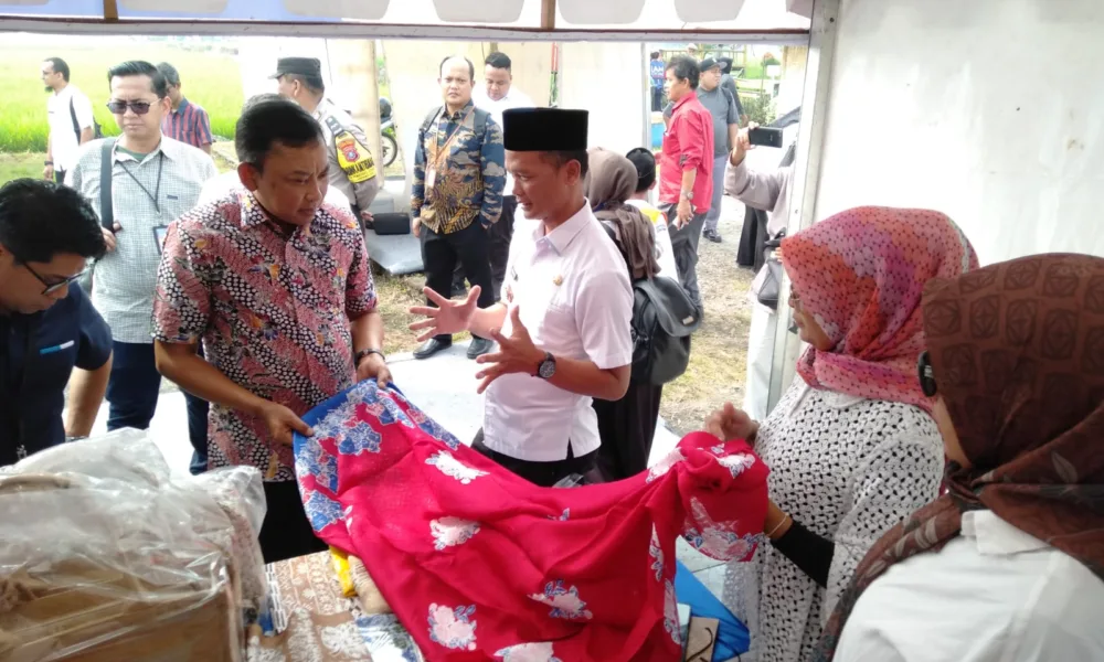 Kepala OJK KR 5 Sumbagut, Bambang Mukti Riyadi (batik merah) mendapatkan penjelasan soal batik motif desa wisata Pematang Johar yang berbahan baku tanaman manggrove dari Kades Pematang Johar, H. Sudarman, Rabu 9 Agustus 2023. (DETAIL/Heno).
