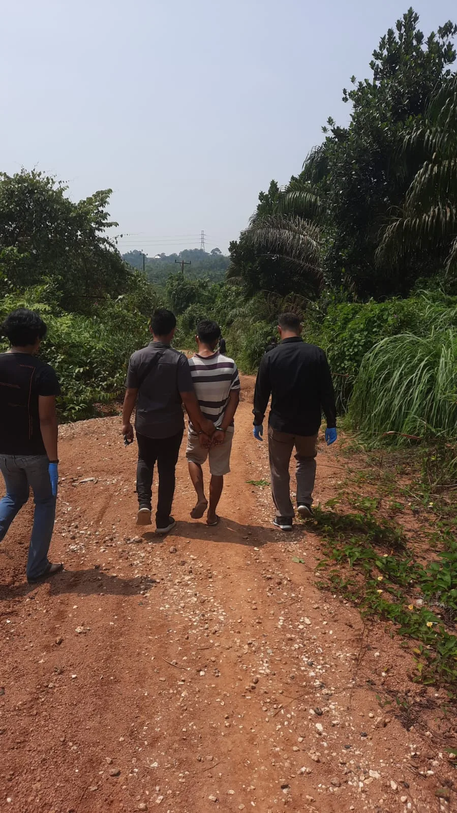 Terduga pelaku pembunuhan berkaos hitam putih saat rekonstruksi di lokasi pembunuhan. (DETAIL/ist)