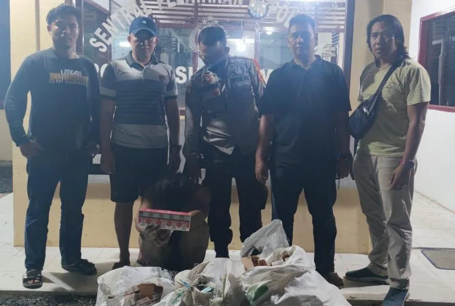 Pelaku pencurian toko sembako, terduduk di depan Polsek sungai Manau dengan bukti kejahatannya.(DETAIL/ist)