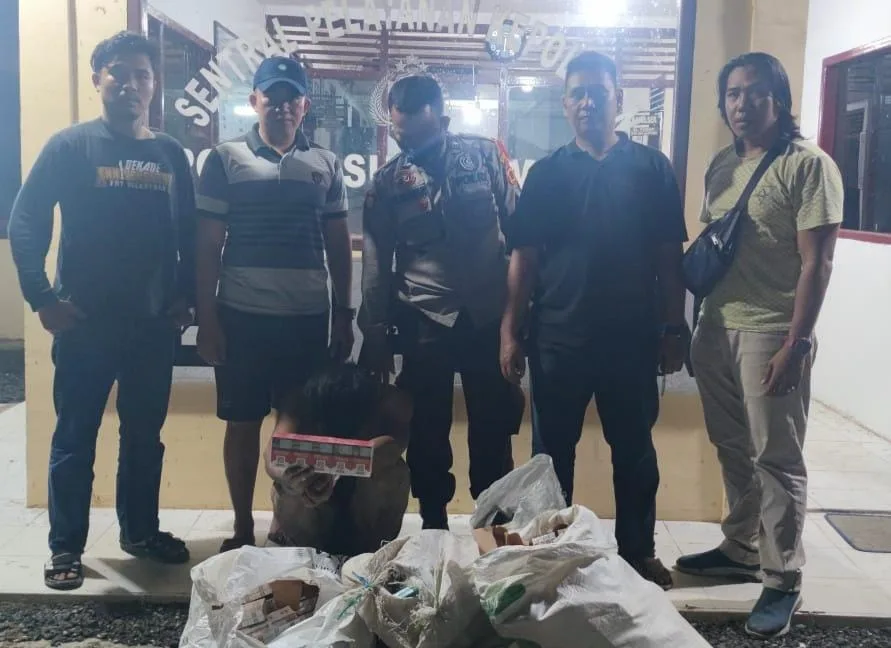 Pelaku pencurian toko sembako, terduduk di depan Polsek sungai Manau dengan bukti kejahatannya.(DETAIL/ist)
