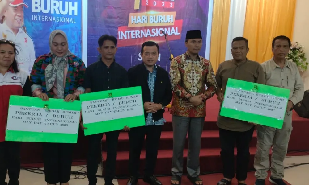 Tiga buruh saat menerima simbolis program bedah rumah pada 1 Mei 2023. Turut hadir Kadisnakertrans, Bahari Panjaitan (paling kanan). (DETAIL/ist)