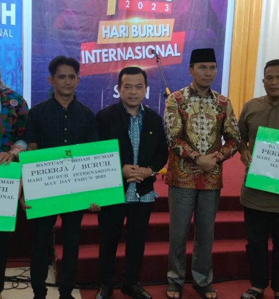 Tiga buruh saat menerima simbolis program bedah rumah pada 1 Mei 2023. Turut hadir Kadisnakertrans, Bahari Panjaitan (paling kanan). (DETAIL/ist)