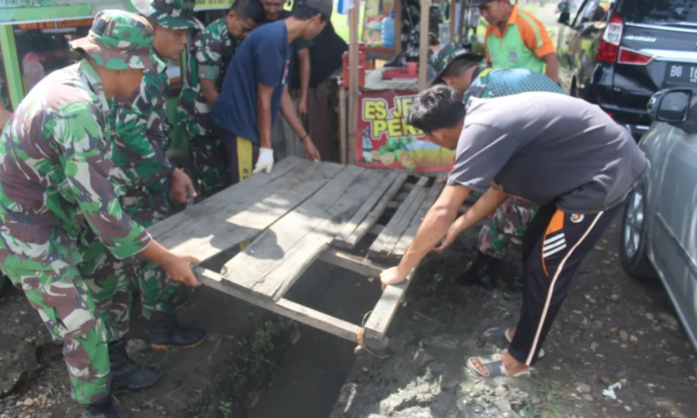 Anggota Kodim Sarko bersama masyarakat membersihkan drainase dan menanam pohon. (DETAIL/ist)
