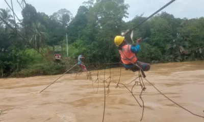 Petugas PLN saat membenahi jaringan kabel listrik yang terhantam banjir di atas jembatan gantung. (DETAIL/Daryanto)