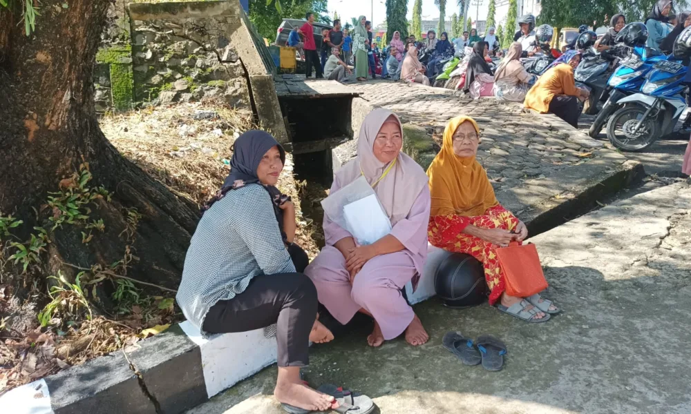 Kerumunan ibu-ibu penerima bantuan pangan yang terlihat kecewa dengan penundaan kunjungan Presiden Jokowi di Merangin. (DETAIL/Daryanto)