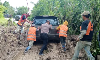 Masyarakat dan Polres Samosir bahu-membahu mendorong sebuah mobil yang terjebak di jalan yang dipenuhi lumpur dan tanah yang disebabkan oleh longsor pada Sabtu pagi, 29 Juni 2024. (ist)