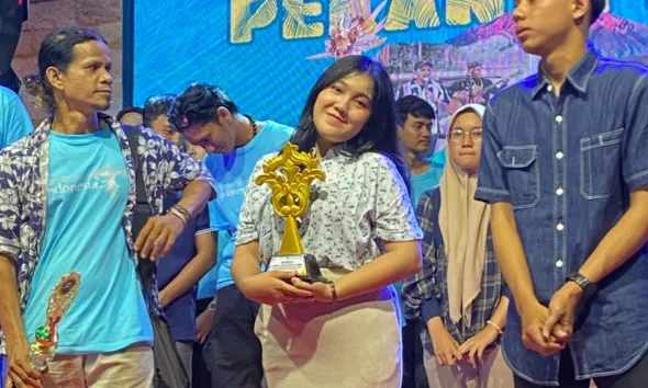 Dewi Mora Manalu saat menerima piala pada pekan pesona budaya. (DETAIL/ist)