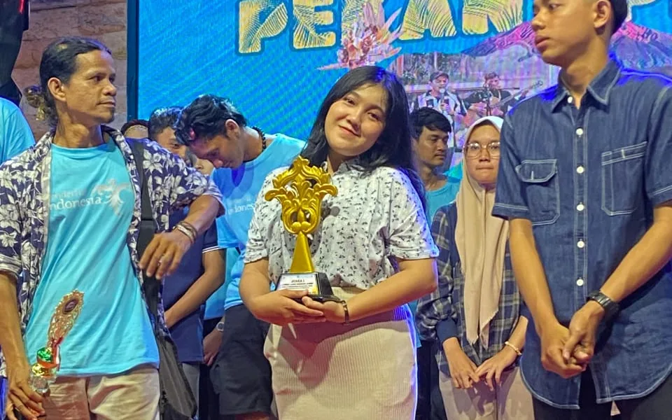 Dewi Mora Manalu saat menerima piala pada pekan pesona budaya. (DETAIL/ist)