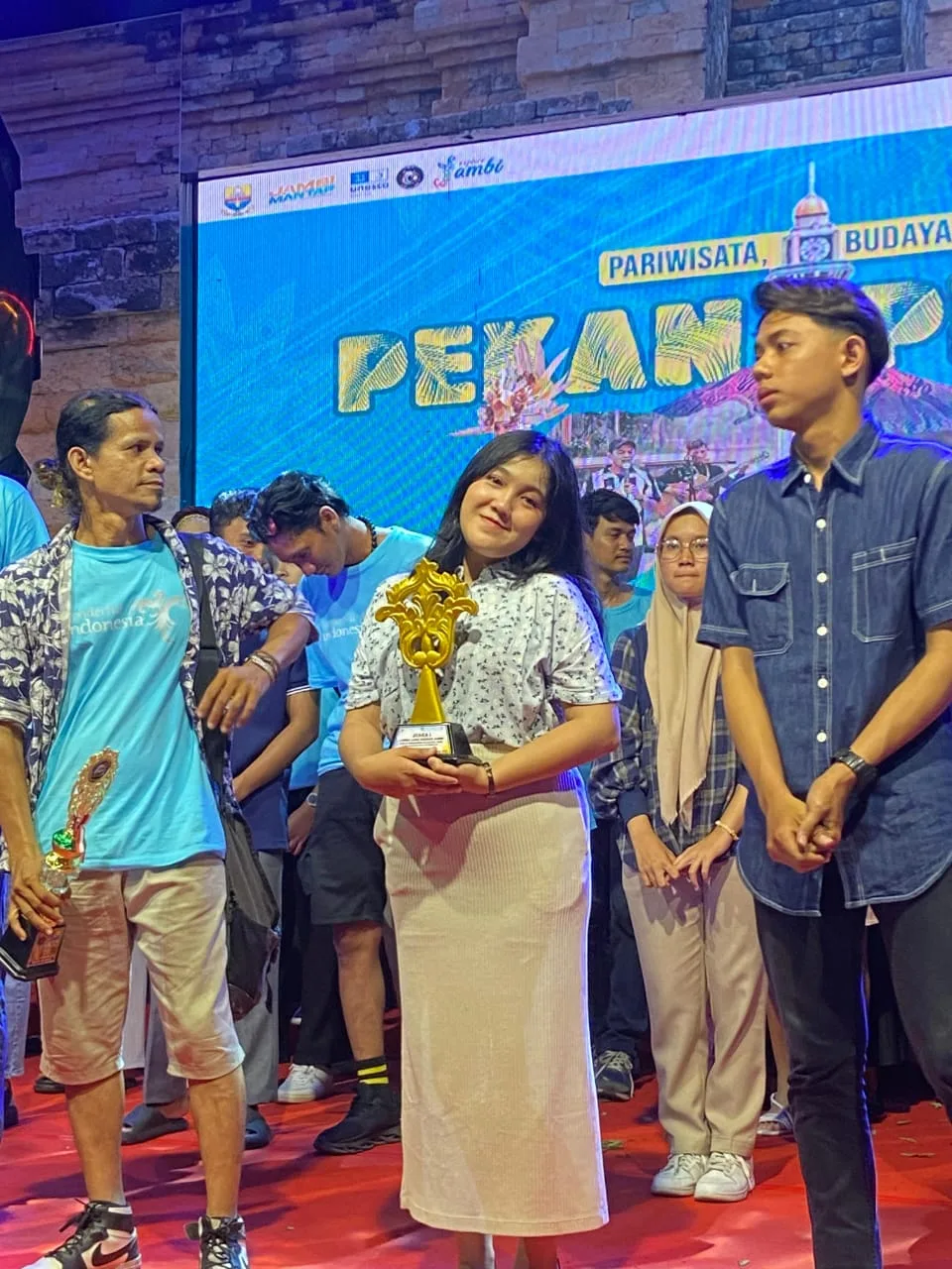 Dewi Mora Manalu saat menerima piala pada pekan pesona budaya. (DETAIL/ist)